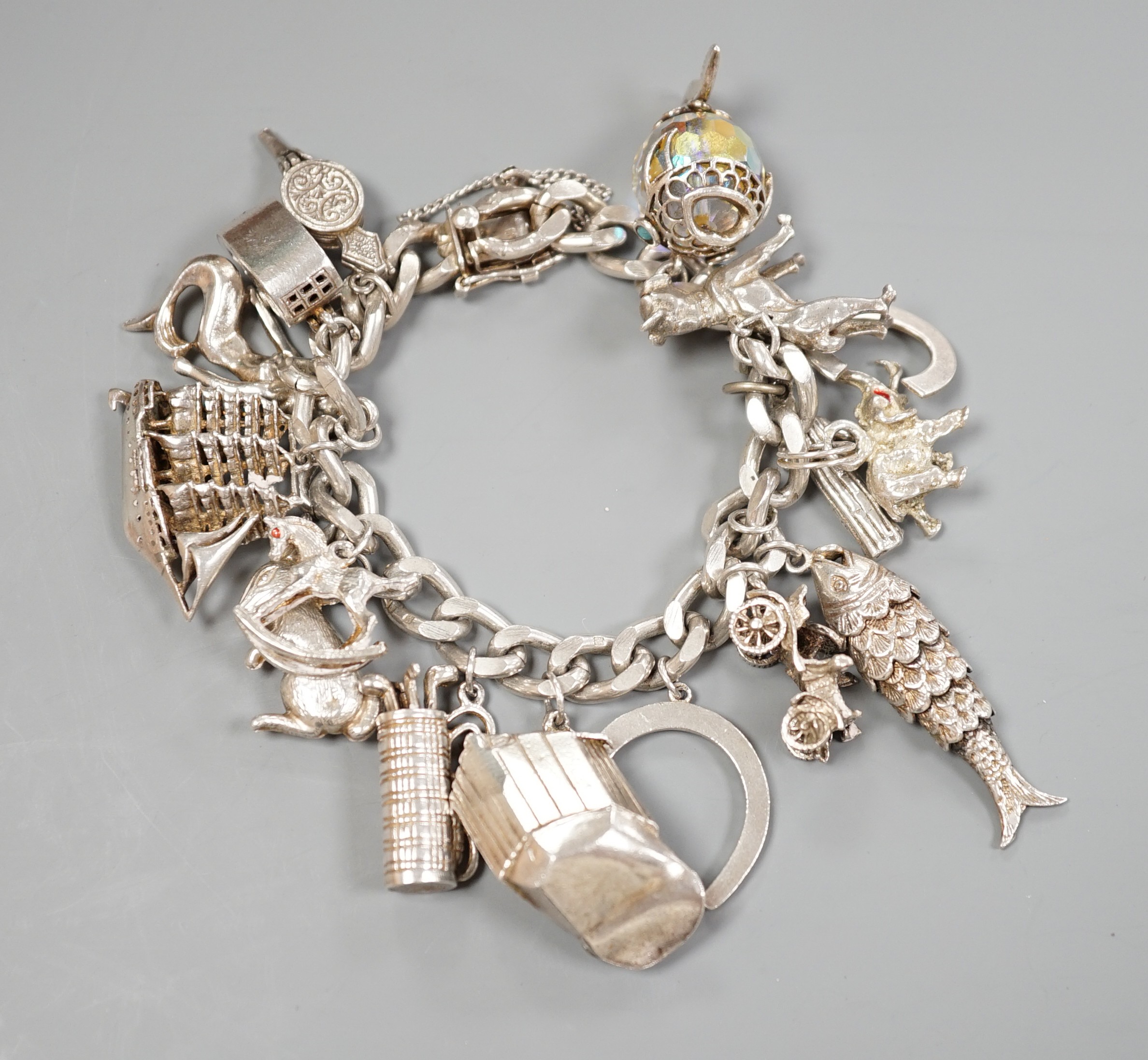 A silver charm bracelet, hung with sixteen assorted charms, gross weight 107.6 grams.
